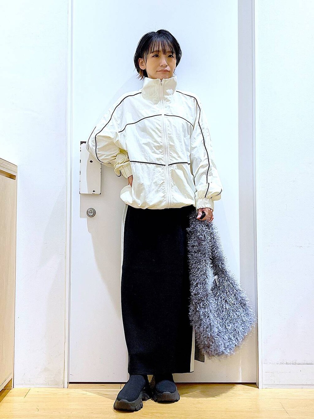 ブラック系のスカート、ベージュ系のブルゾン、グレー系のショルダーバッグを着用したレディースの秋コーディネートの2枚目の写真