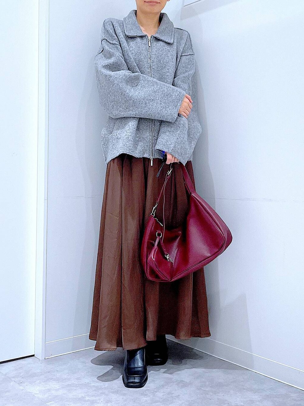 グレー系のブルゾン、ブラック系のブーツ、レッド系のショルダーバッグを着用したレディースの冬コーディネートの6枚目の写真