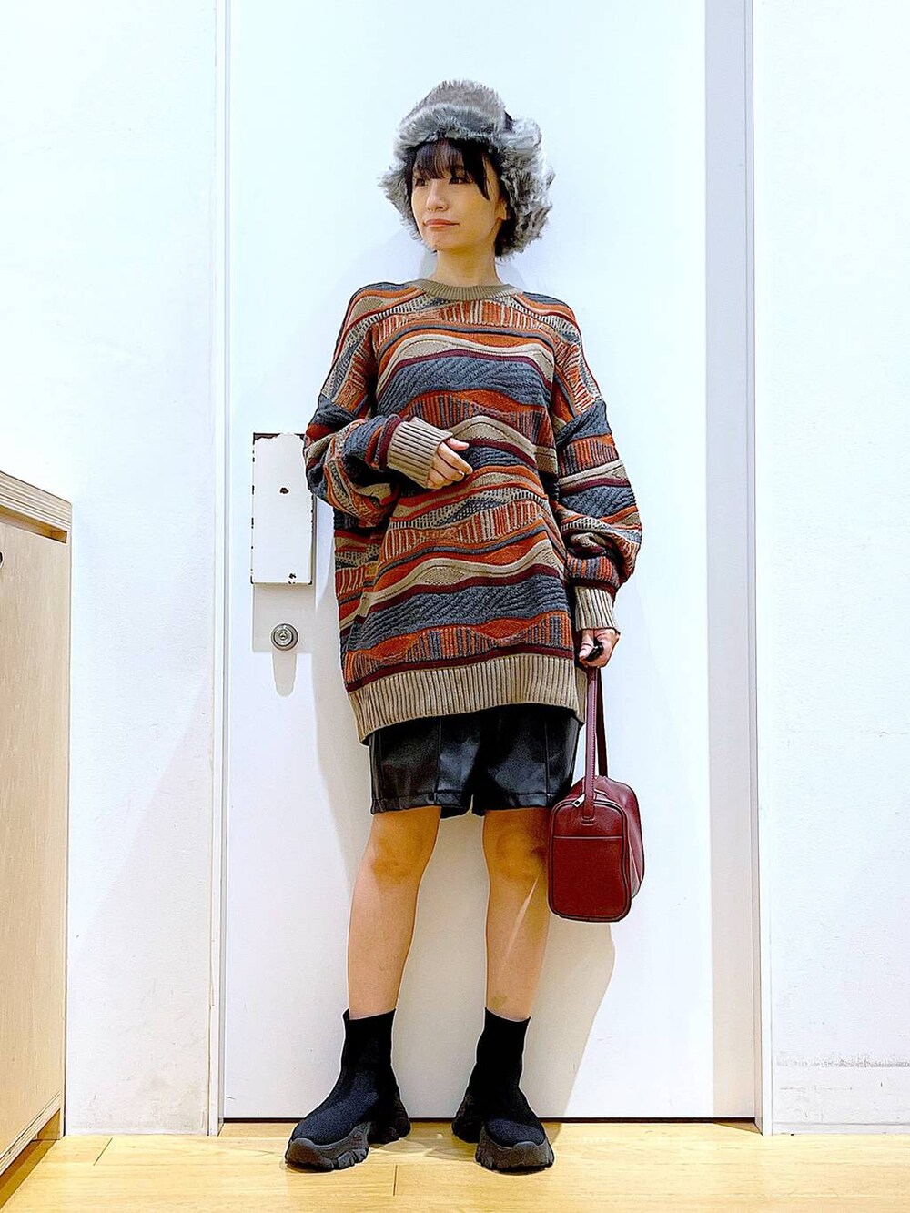 レッド系のショルダーバッグ、ブラック系のブーツ、ブラック系のその他パンツを着用したレディースの冬コーディネートの2枚目の写真