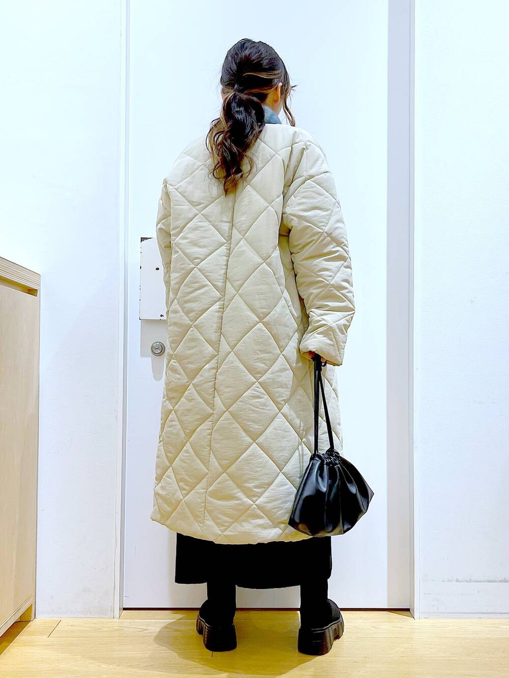 ブラック系のショルダーバッグ、ブラック系のブーツ、ベージュ系のノーカラーコートを着用したレディースの冬コーディネートの5枚目の写真