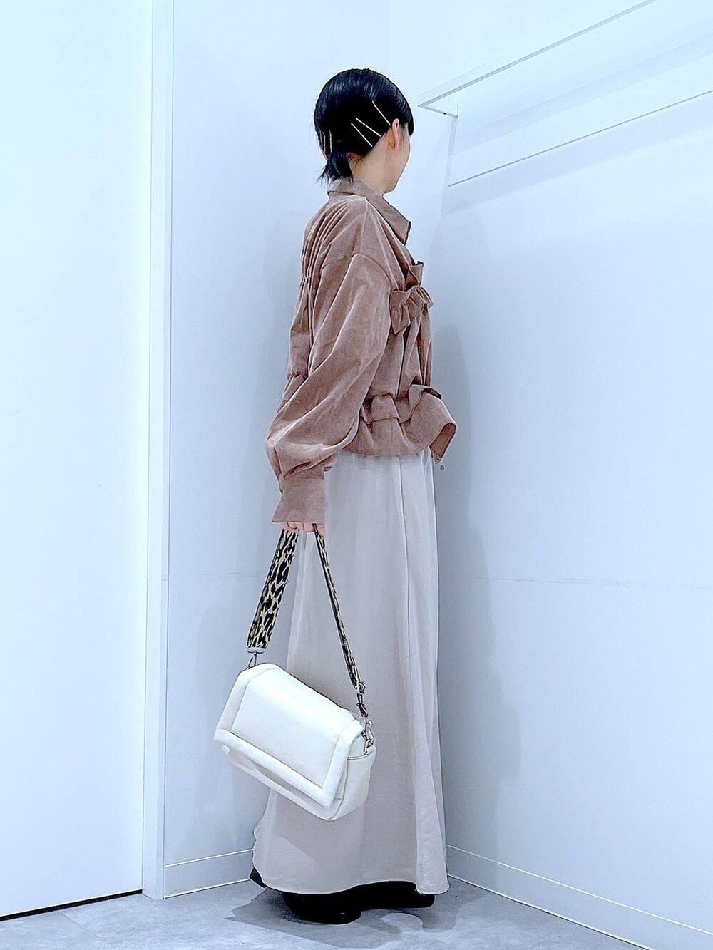 ベージュ系のスカート、ホワイト系のショルダーバッグ、ブラック系のブーツを着用したレディースの秋コーディネートの4枚目の写真