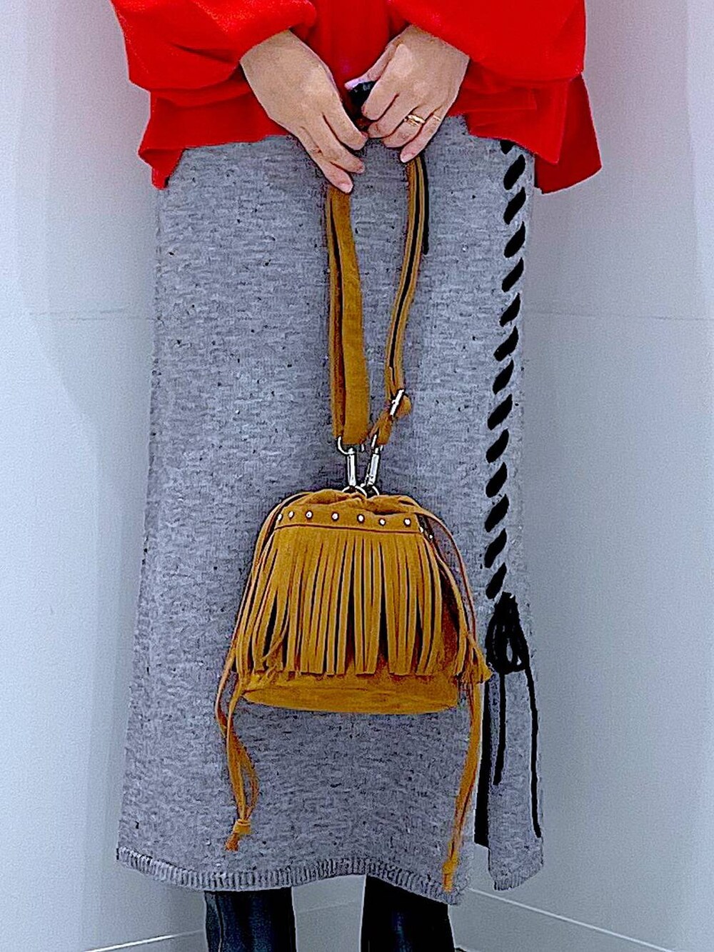 レッド系のニット/セーター、グレー系のスカート、ブラック系のブーツを着用したレディースの秋コーディネートの9枚目の写真