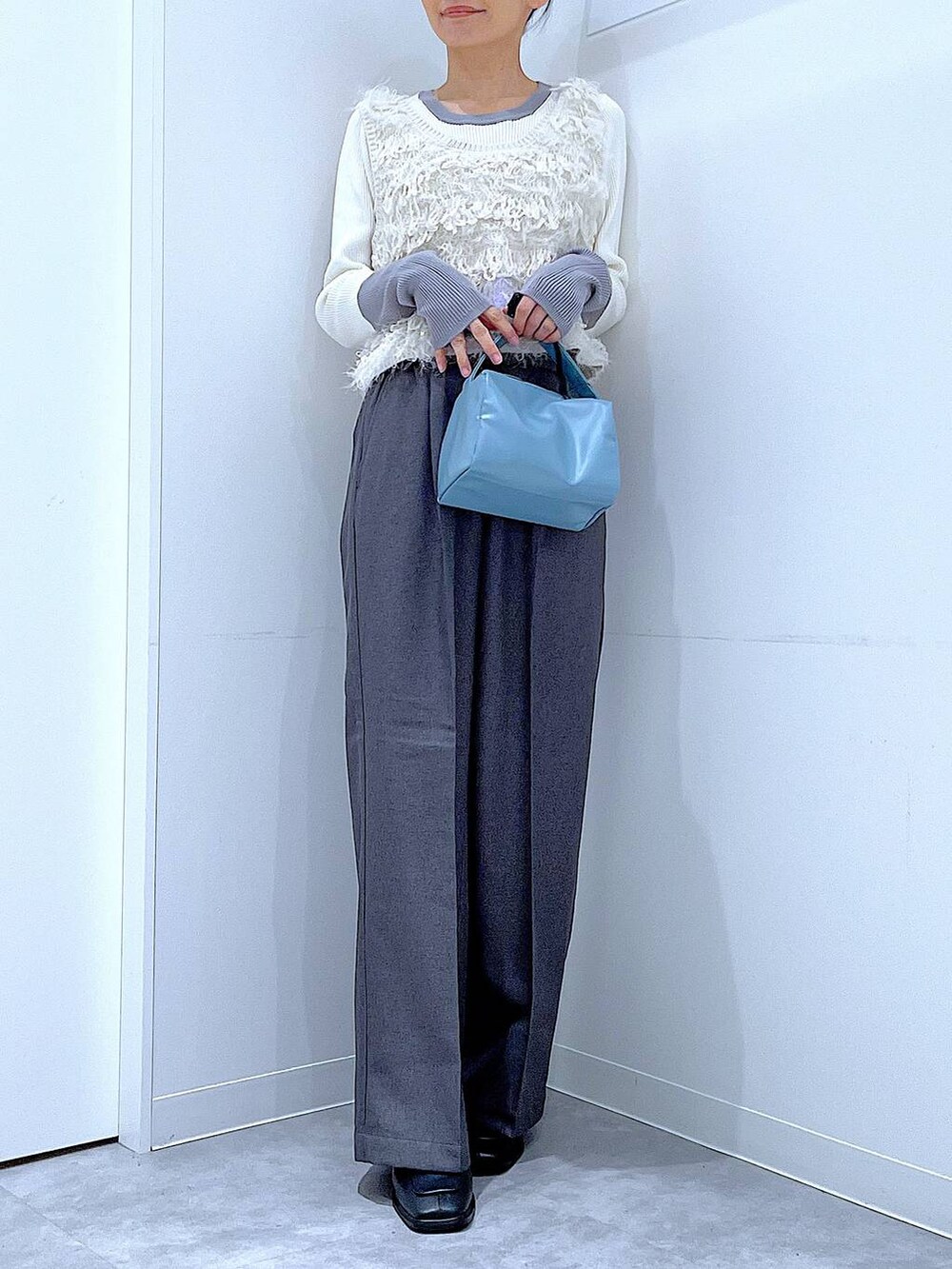 ブラック系のブーツ、グレー系のスラックス、ホワイト系のベストを着用したレディースの冬コーディネートの6枚目の写真