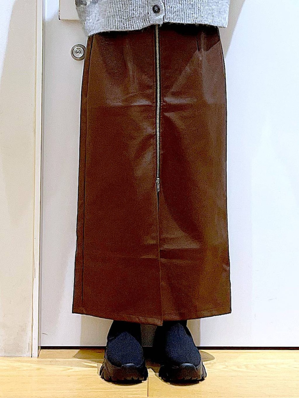 ブラウン系のスカート、ブラック系のショルダーバッグ、ブラック系のブーツを着用したレディースの冬コーディネートの8枚目の写真