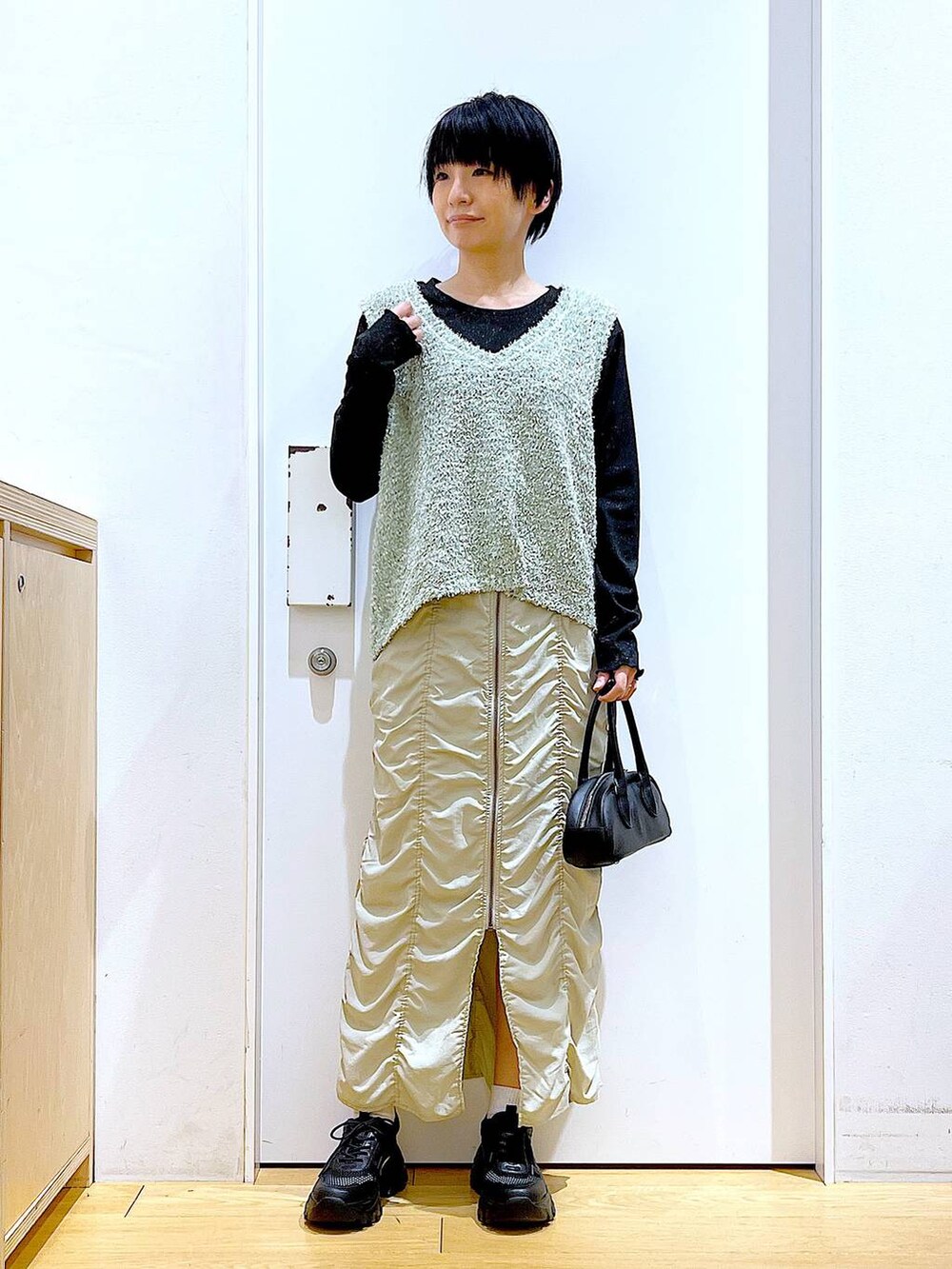 ベージュ系のスカート、ブラック系のボストンバッグ、ブラック系のTシャツ/カットソーを着用したレディースの春コーディネートの2枚目の写真