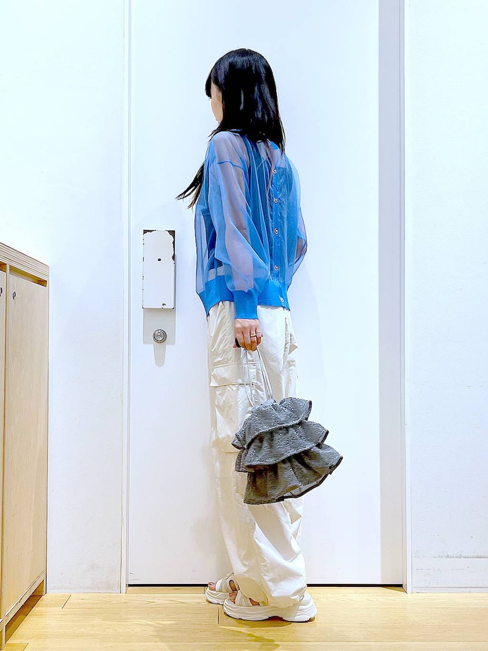 シルバー系のショルダーバッグ、ホワイト系のカーゴパンツ、ブラック系のニット/セーターを着用したレディースの夏コーディネートの3枚目の写真