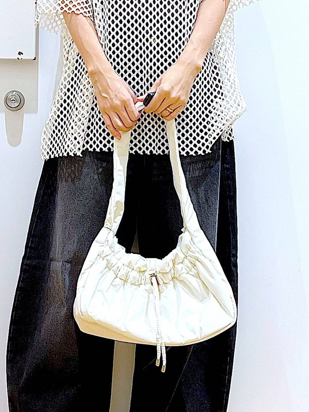 ホワイト系のハンドバッグ、ブラック系のニット/セーター、ホワイト系のTシャツ/カットソーを着用したレディースの夏コーディネートの9枚目の写真