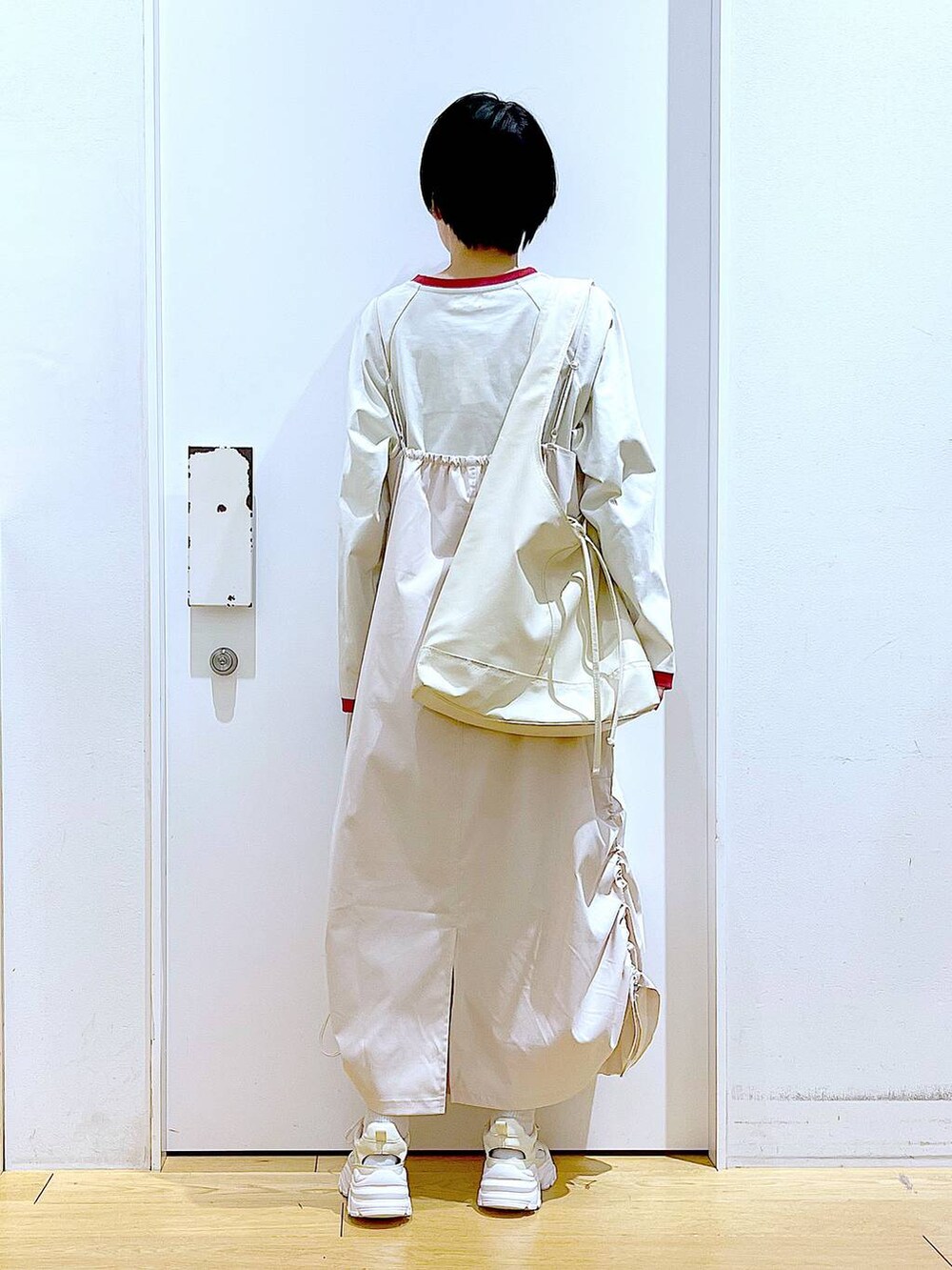 ホワイト系のスニーカー、ベージュ系のジャンパースカート、ベージュ系のTシャツ/カットソーを着用したレディースの春コーディネートの5枚目の写真