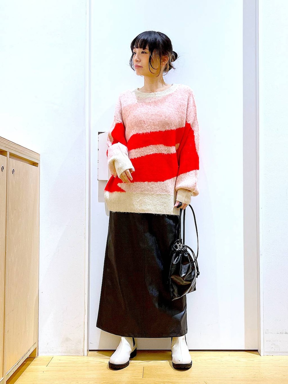 ベージュ系のブーツ、ブラック系のスカート、ブラック系のショルダーバッグを着用したレディースの冬コーディネートの2枚目の写真