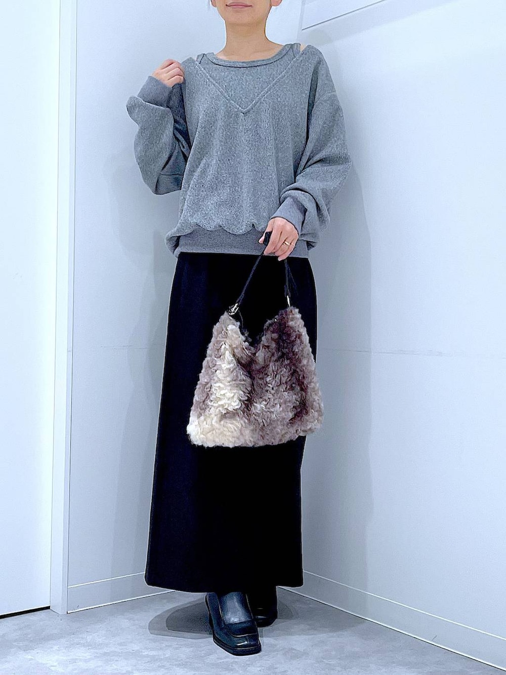 ブラック系のスカート、ブラック系のブーツ、ブラウン系のショルダーバッグを着用したレディースの冬コーディネートの6枚目の写真