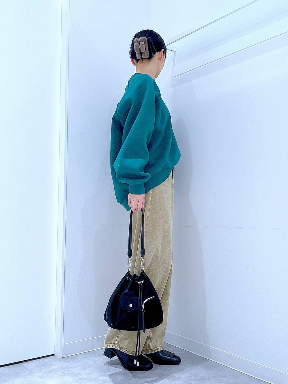 ベージュ系のデニムパンツ、ブラック系のショルダーバッグ、ブラック系のブーツを着用したレディースの冬コーディネートの4枚目の写真