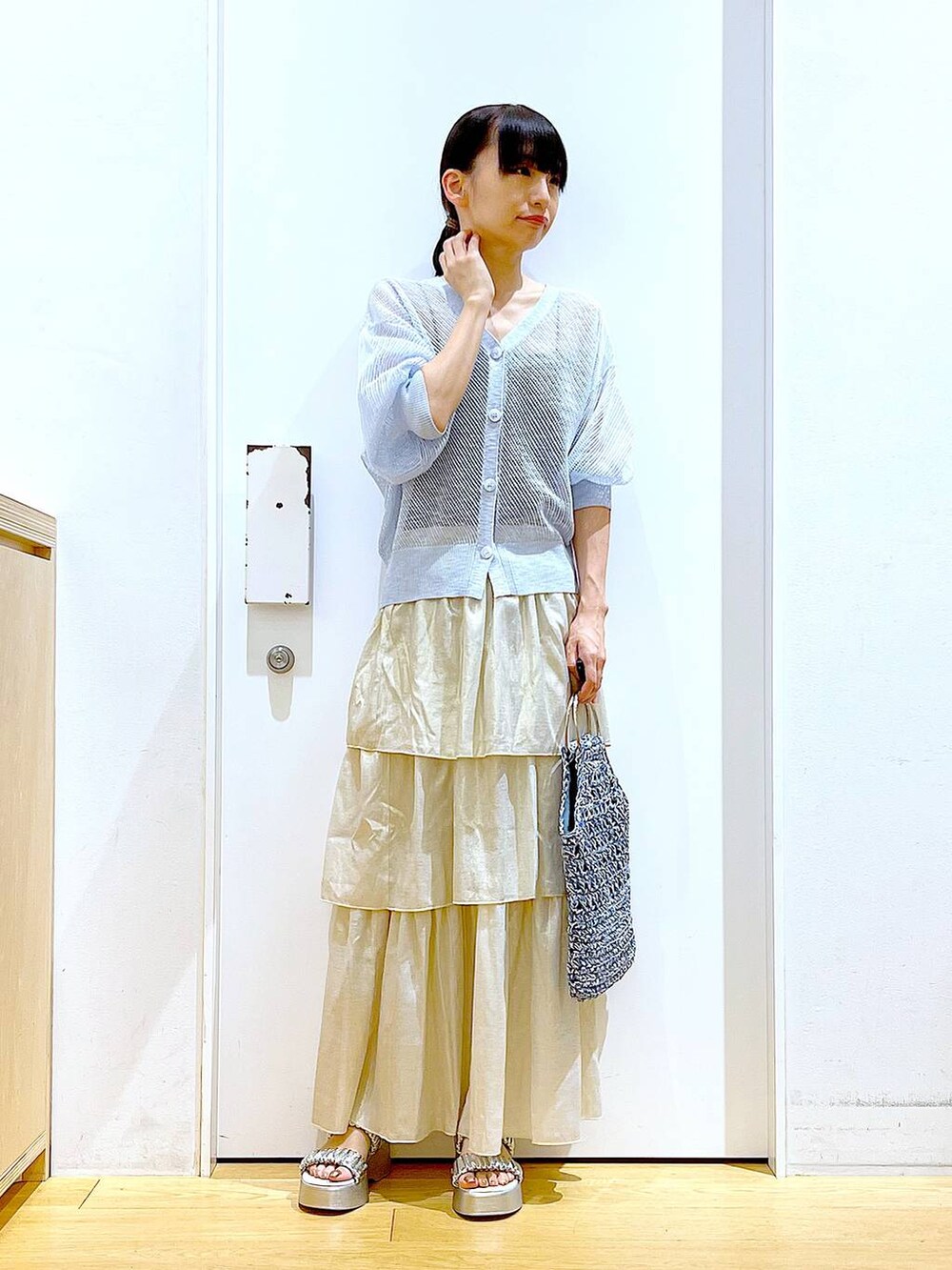 シルバー系のサンダル、ブルー系のハンドバッグ、ゴールド系のスカートを着用したレディースの夏コーディネートの2枚目の写真