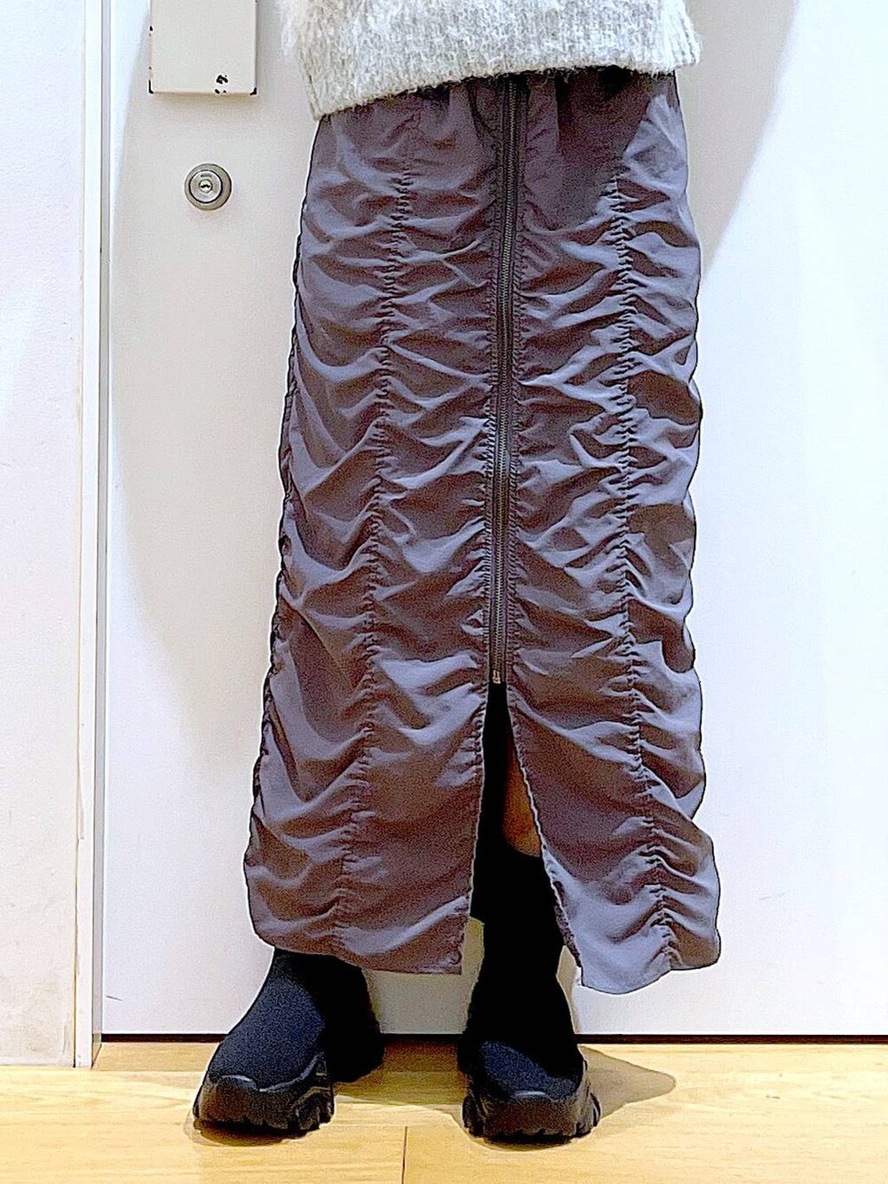 グレー系のショルダーバッグ、グレー系のスカート、ブラック系のブーツを着用したレディースの冬コーディネートの8枚目の写真