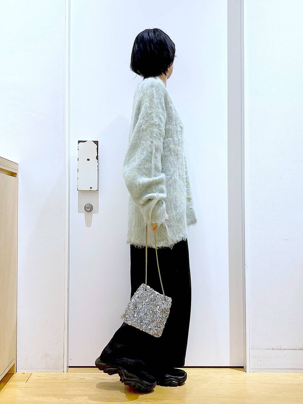 グリーン系のカーディガン/ボレロ、ブラック系のブーツ、ブラック系のスカートを着用したレディースの冬コーディネートの4枚目の写真