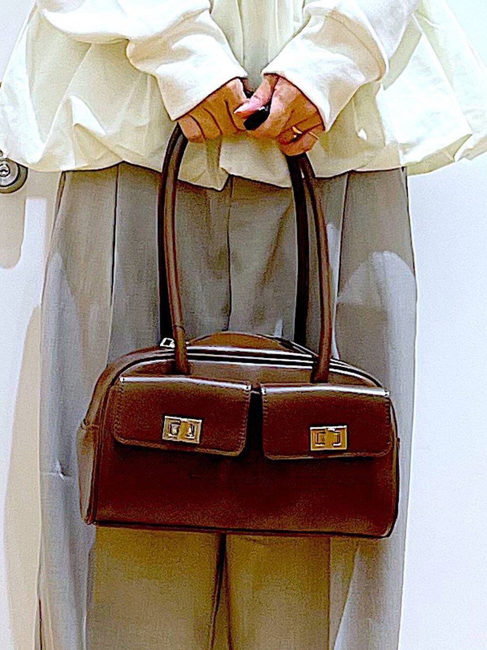 ブラウン系のハンドバッグ、ベージュ系のブーツ、ベージュ系のスウェットを着用したレディースの冬コーディネートの9枚目の写真