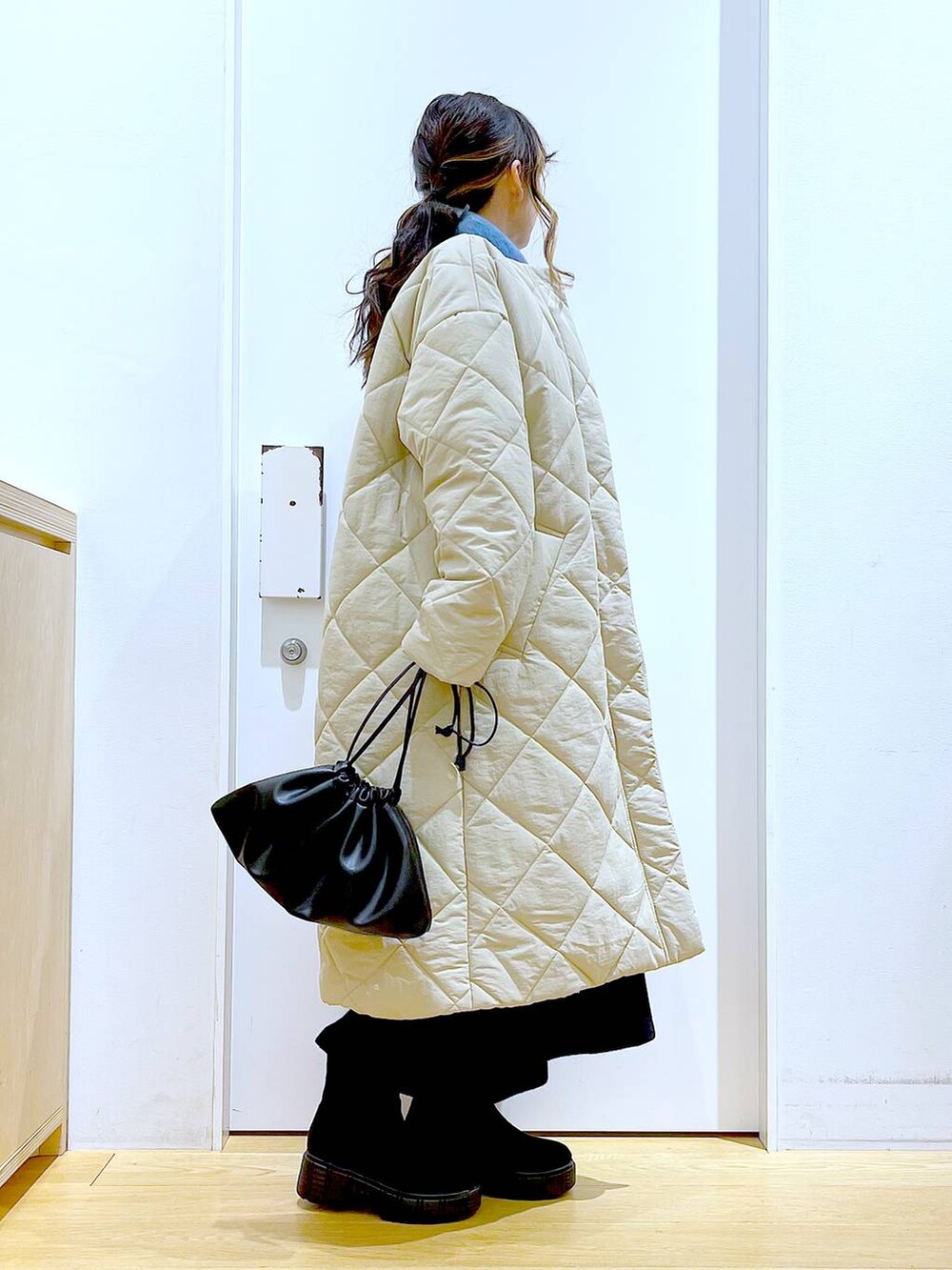 ブラック系のショルダーバッグ、ブラック系のブーツ、ベージュ系のノーカラーコートを着用したレディースの冬コーディネートの4枚目の写真