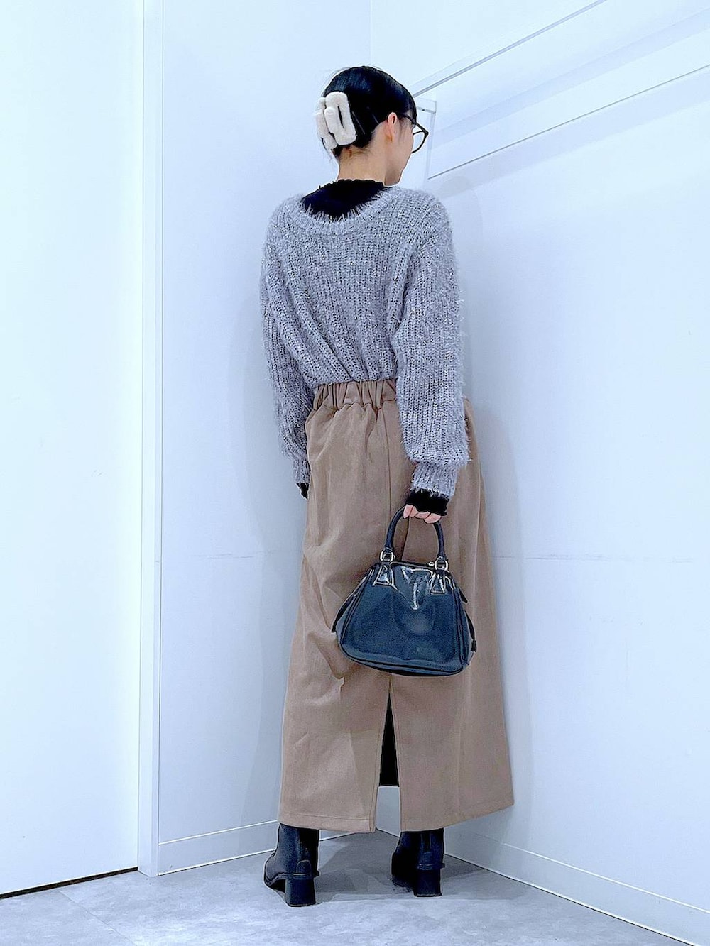 ブラック系のブーツ、ブラック系のショルダーバッグ、ブラウン系のスカートを着用したレディースの冬コーディネートの5枚目の写真