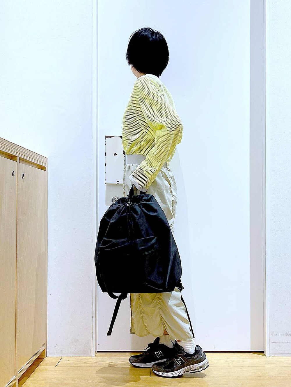 ベージュ系のスカート、ブラック系のバックパック/リュック、イエロー系のTシャツ/カットソーを着用したレディースの春コーディネートの3枚目の写真