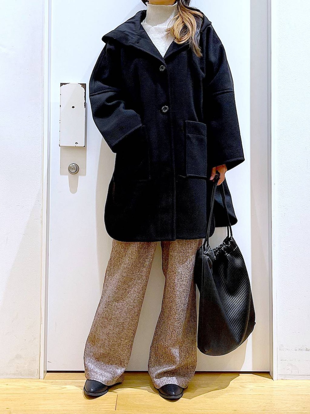 ブラック系のその他アウター、ブラック系のブーツ、ブラック系のトートバッグを着用したレディースの冬コーディネートの6枚目の写真
