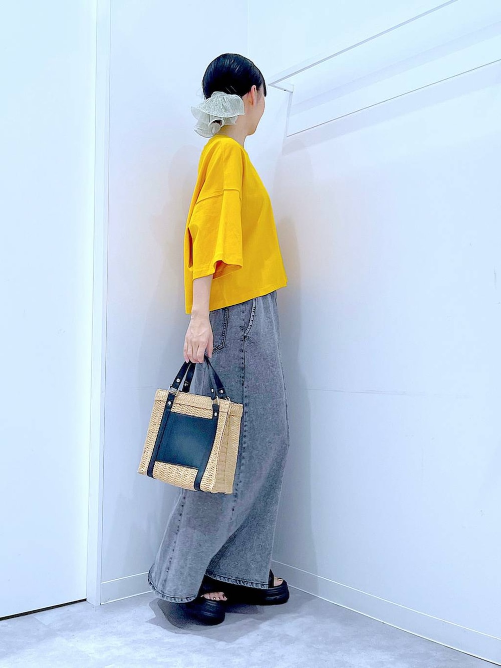 ベージュ系のショルダーバッグ、ブラック系のサンダル、オレンジ系のTシャツ/カットソーを着用したレディースの夏コーディネートの4枚目の写真