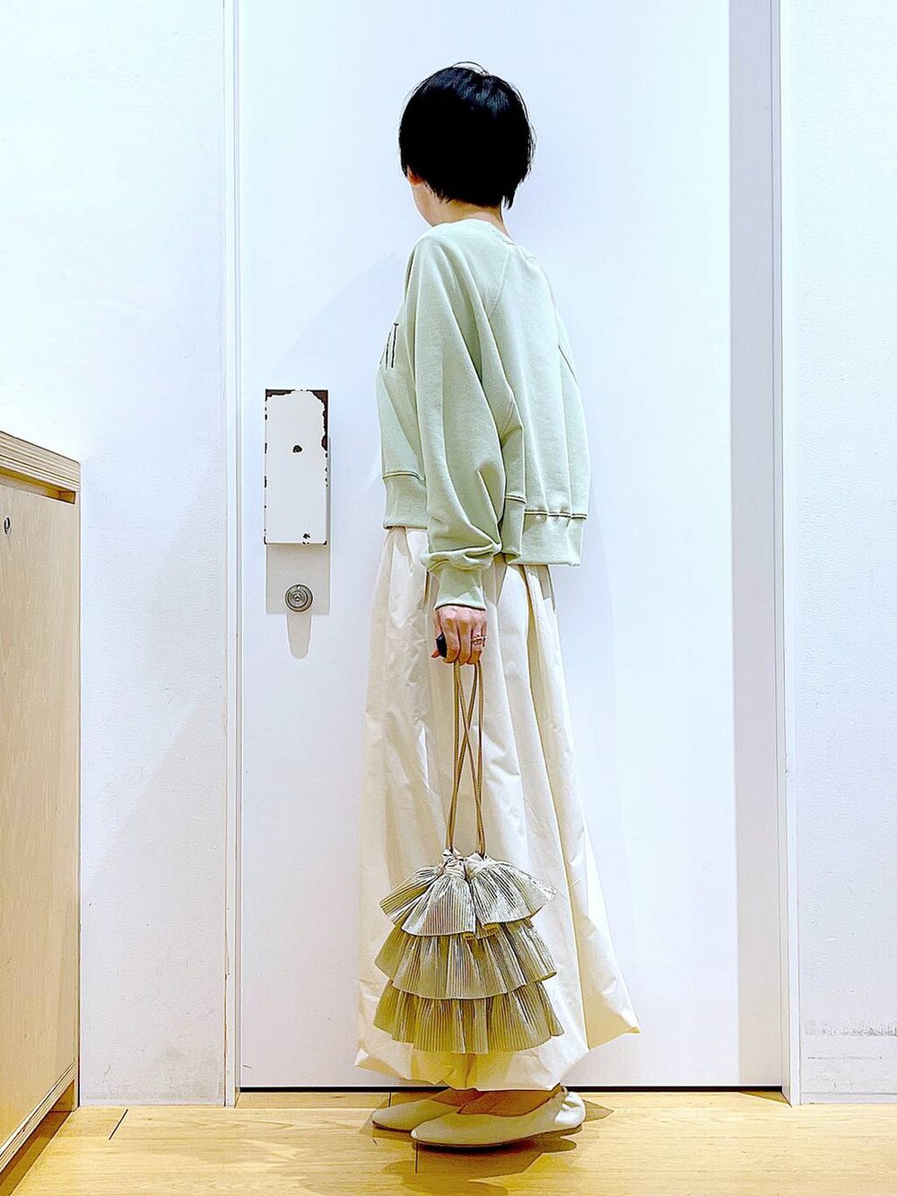 ホワイト系のパンプス、ベージュ系のショルダーバッグ、グリーン系のスウェットを着用したレディースの春コーディネートの3枚目の写真