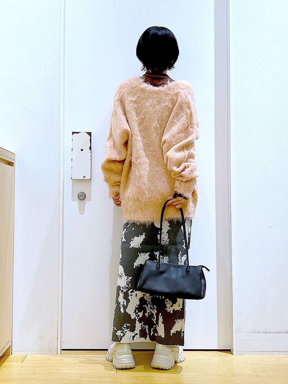 グレー系のスカート、ブラック系のトートバッグ、ピンク系のカーディガン/ボレロを着用したレディースの秋コーディネートの5枚目の写真