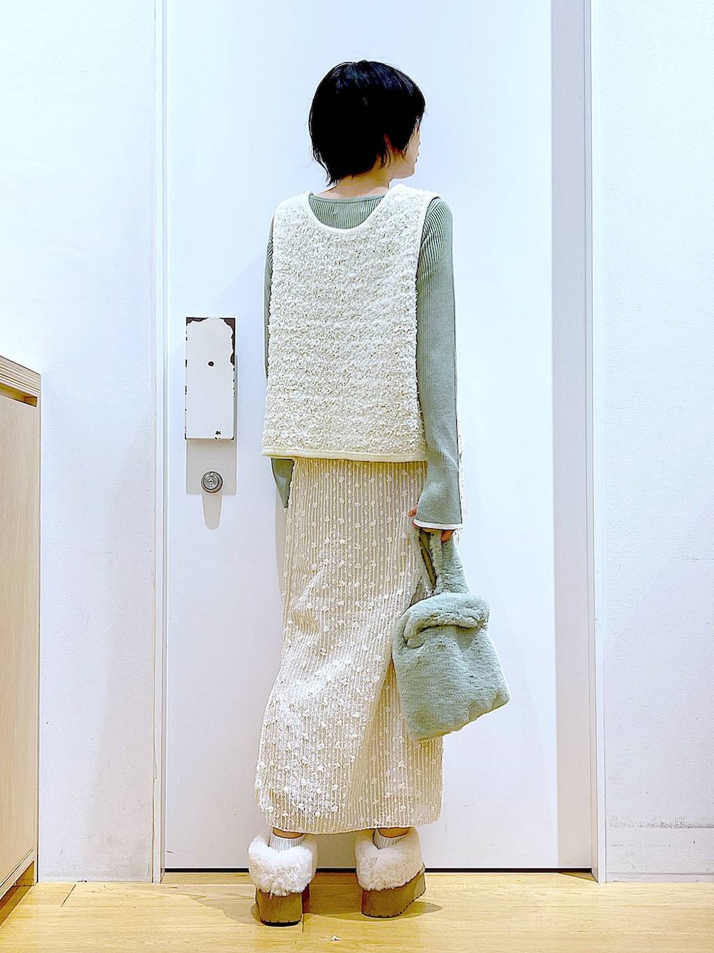 グリーン系のニット/セーター、グリーン系のショルダーバッグ、ベージュ系のベストを着用したレディースの秋コーディネートの5枚目の写真