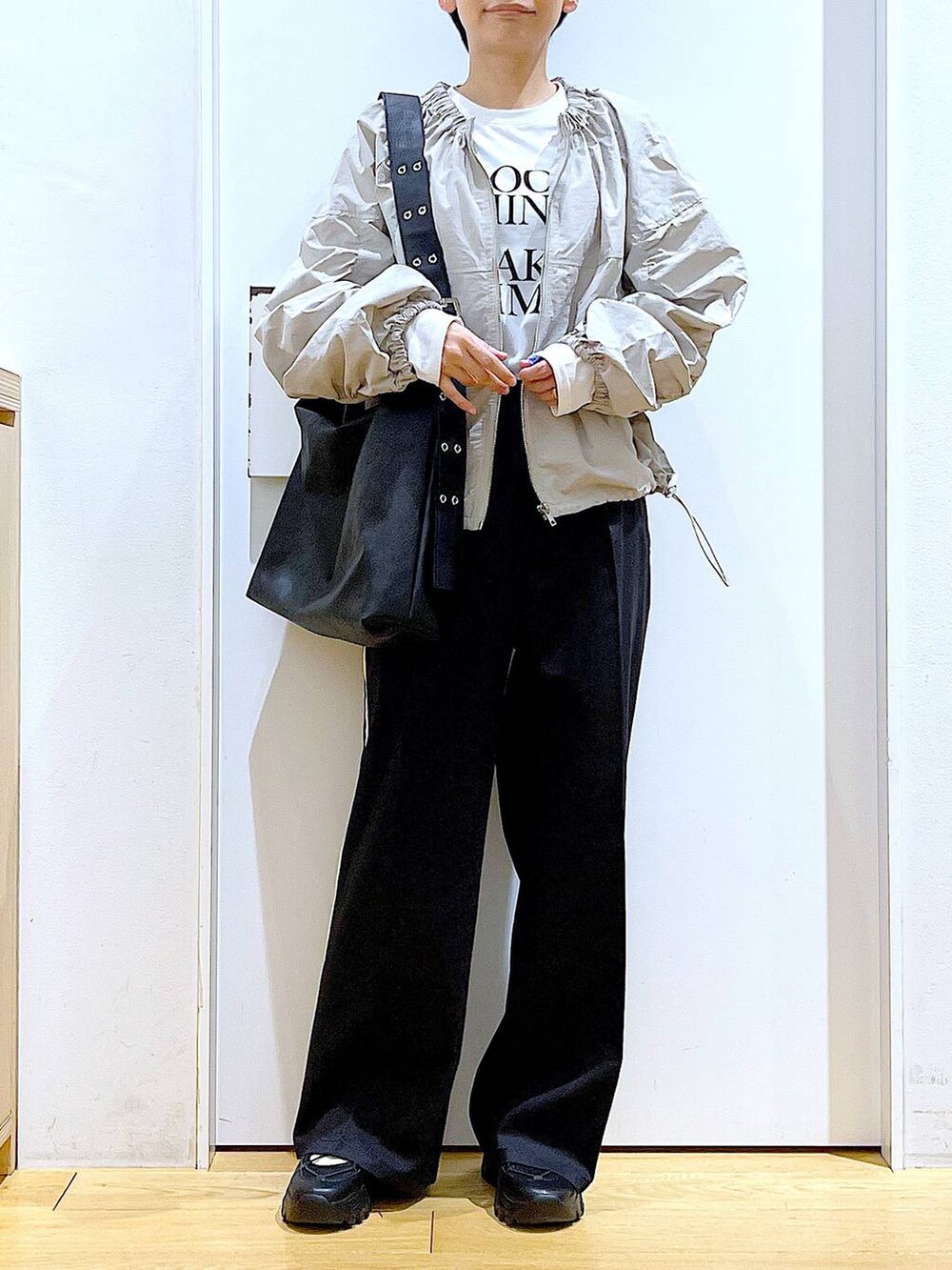 ブラック系のスラックス、ブラック系のスニーカー、ブラック系のショルダーバッグを着用したレディースの春コーディネートの6枚目の写真