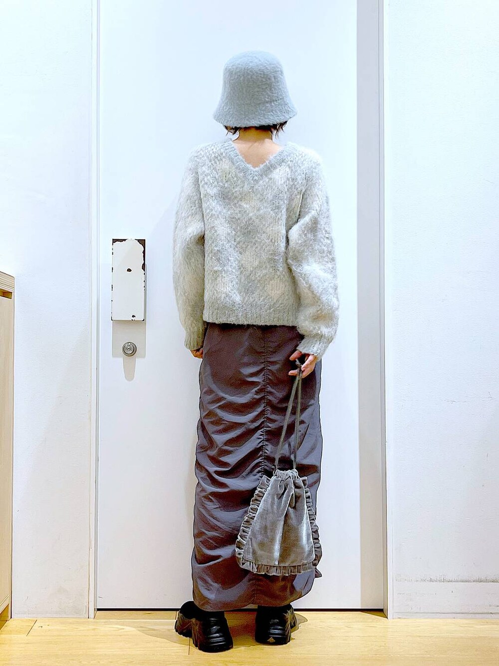 グレー系のショルダーバッグ、グレー系のスカート、ブラック系のブーツを着用したレディースの冬コーディネートの5枚目の写真