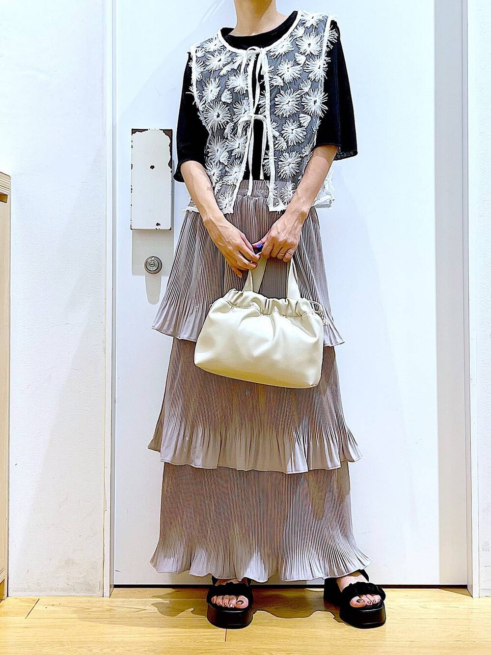 グレー系のスカート、ブラック系のサンダル、ホワイト系のショルダーバッグを着用したレディースの夏コーディネートの6枚目の写真