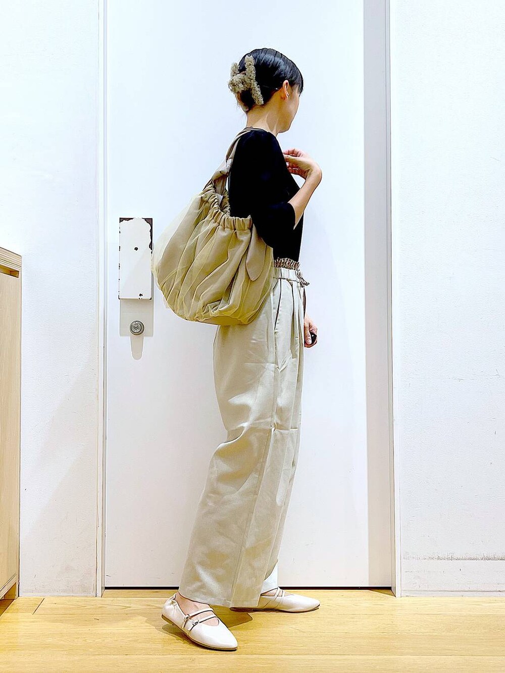 ベージュ系のトートバッグ、ホワイト系のパンプス、ブラック系のTシャツ/カットソーを着用したレディースの秋コーディネートの4枚目の写真