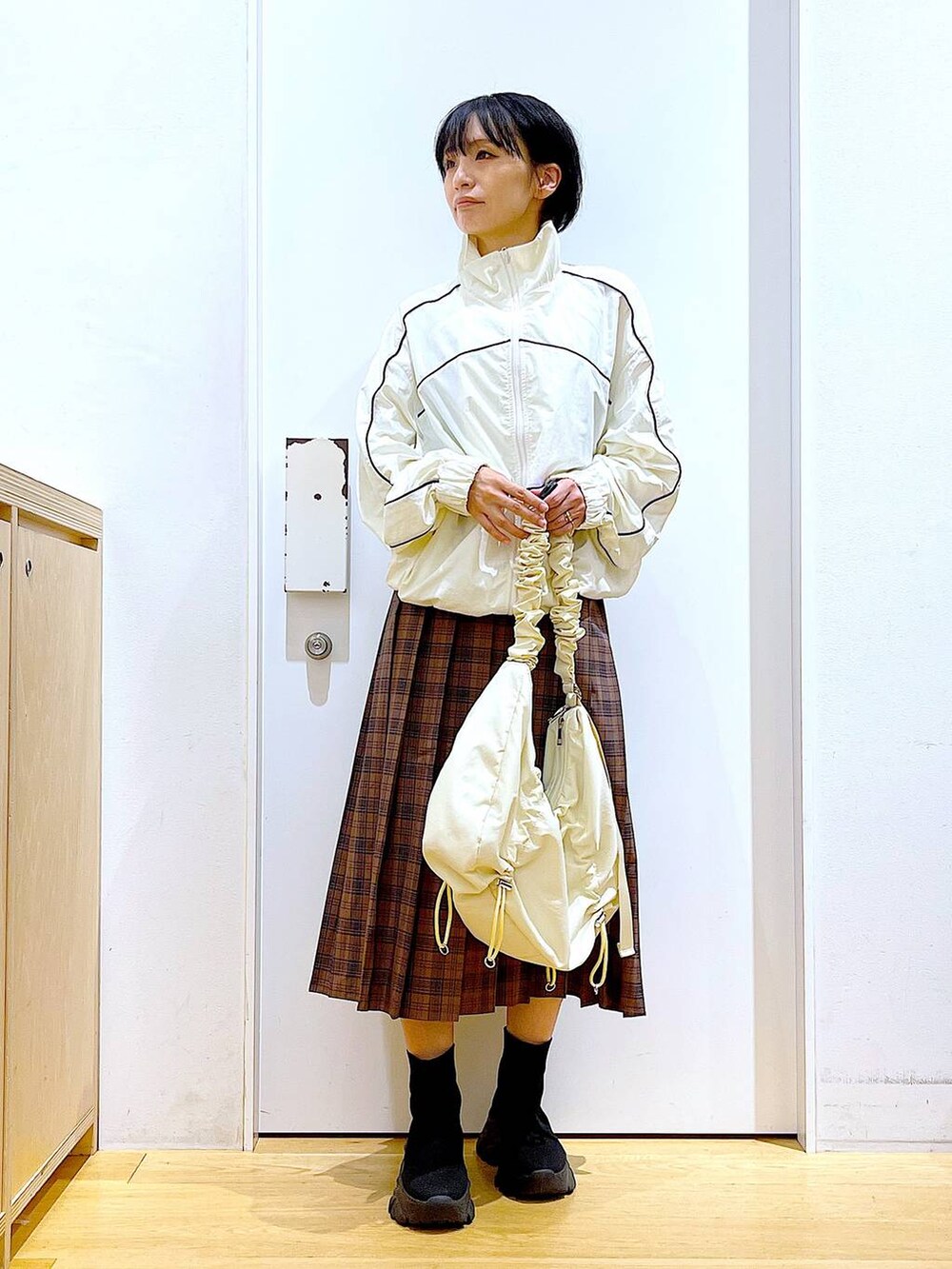 ホワイト系のショルダーバッグ、ベージュ系のブルゾン、ブラック系のブーツを着用したレディースの秋コーディネートの2枚目の写真