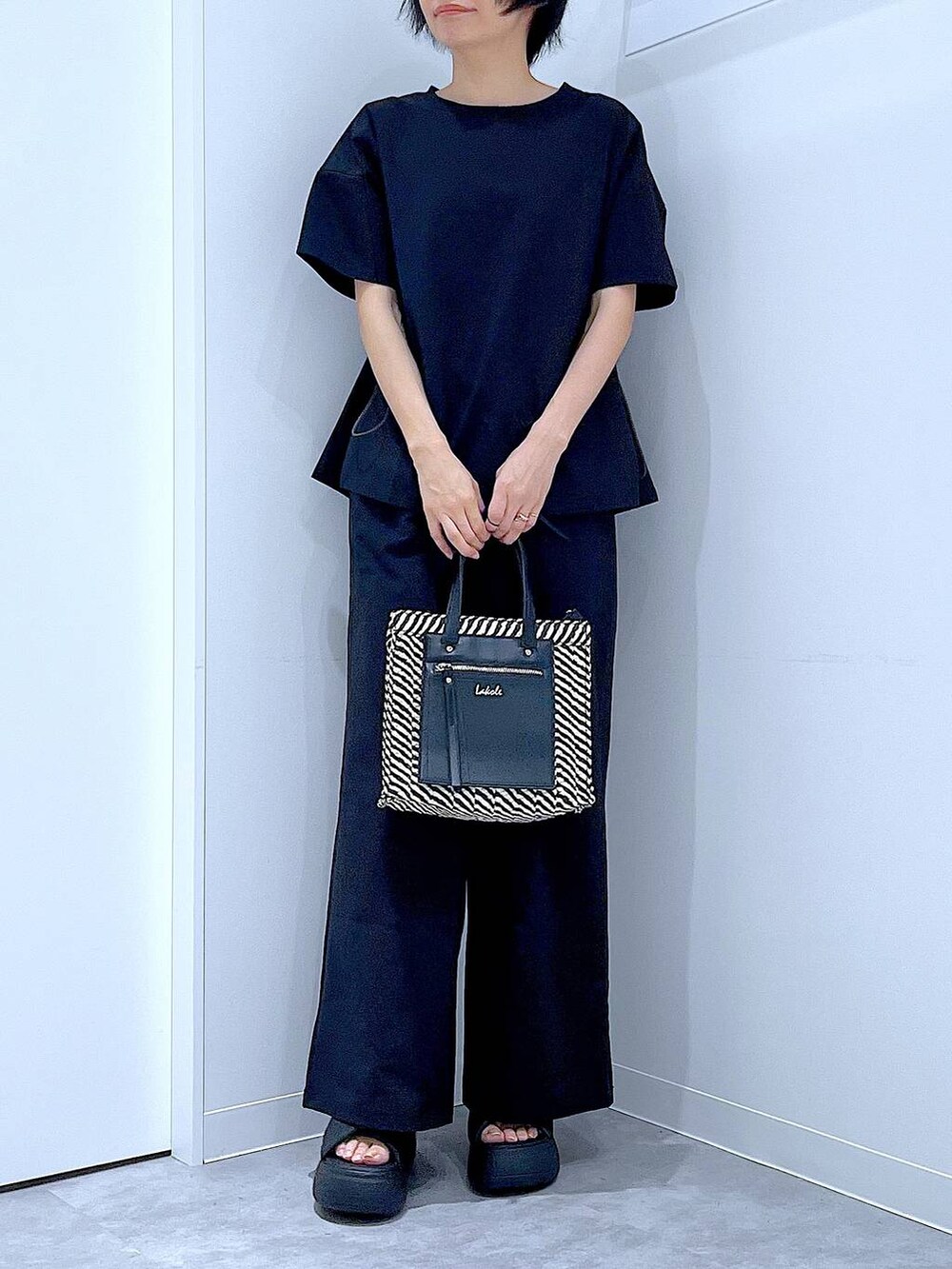 ブラック系のショルダーバッグ、ブラック系のサンダル、ブラック系のTシャツ/カットソーを着用したレディースの夏コーディネートの6枚目の写真