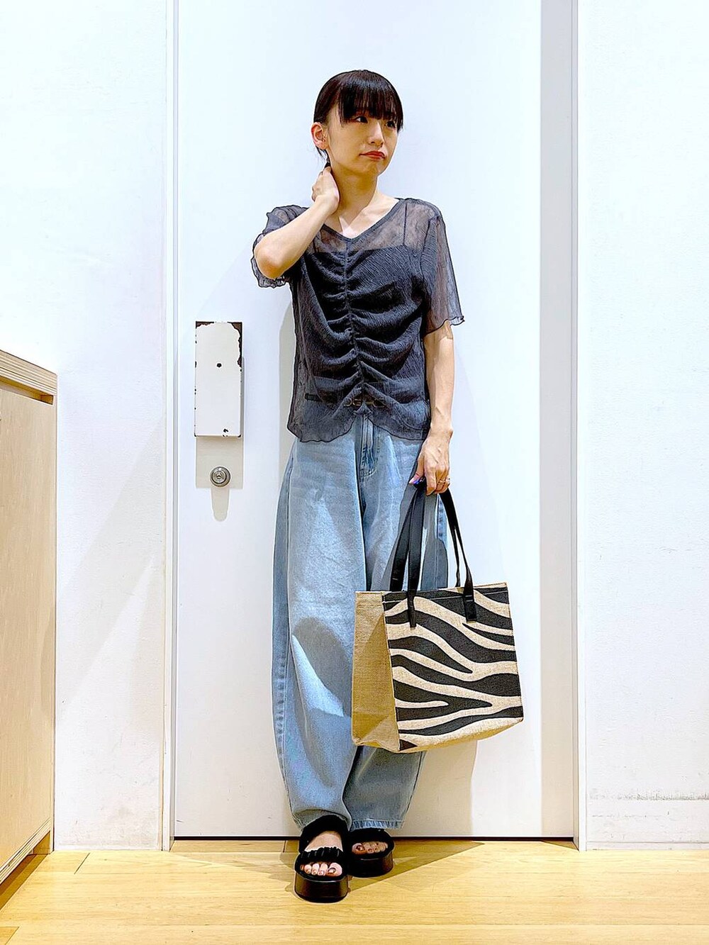 ブルー系のデニムパンツ、その他のトートバッグ、ブラック系のサンダルを着用したレディースの夏コーディネートの2枚目の写真