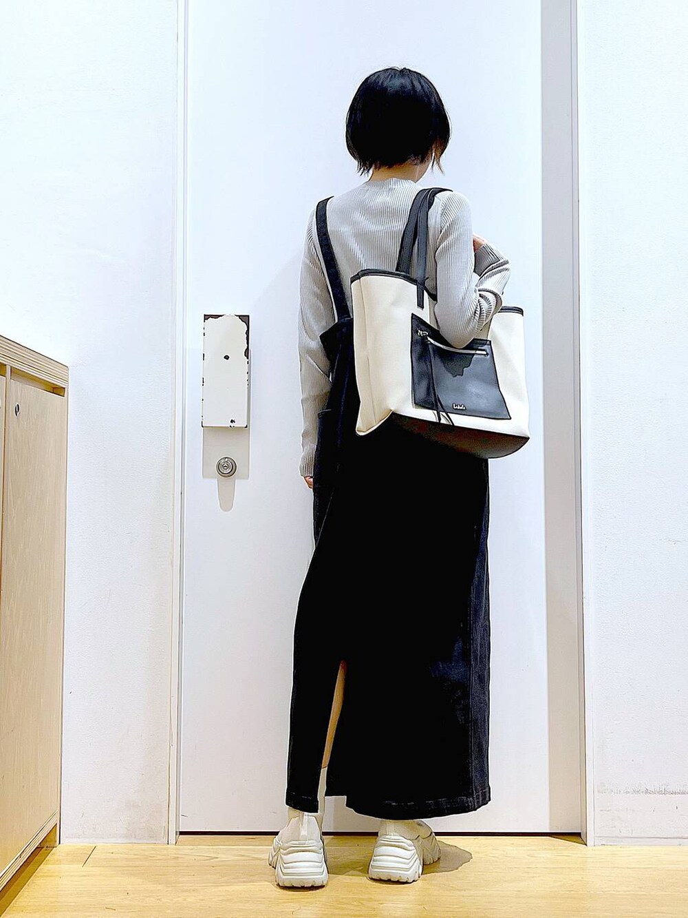 グレー系のジャンパースカート、ホワイト系のトートバッグ、グレー系のニット/セーターを着用したレディースの秋コーディネートの5枚目の写真