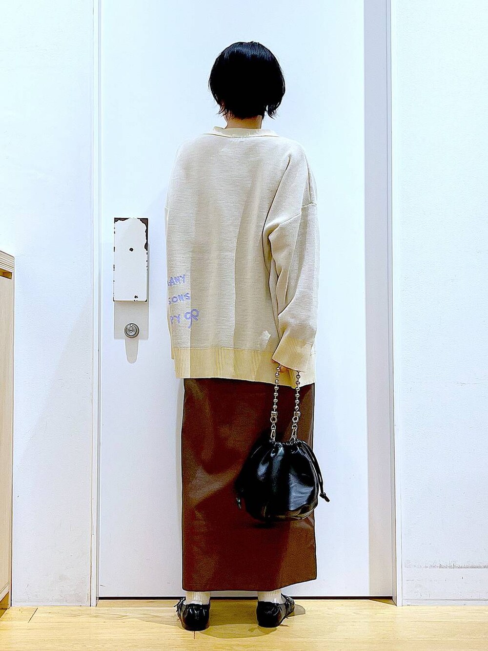 ブラウン系のスカート、ブラック系のショルダーバッグ、ブラック系のパンプスを着用したレディースの秋コーディネートの5枚目の写真