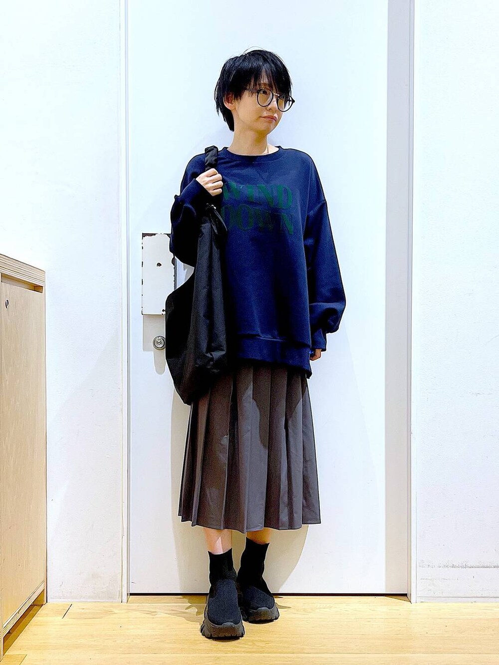 ブラック系のショルダーバッグ、ブラック系のブーツ、グレー系のスカートを着用したレディースの冬コーディネートの2枚目の写真