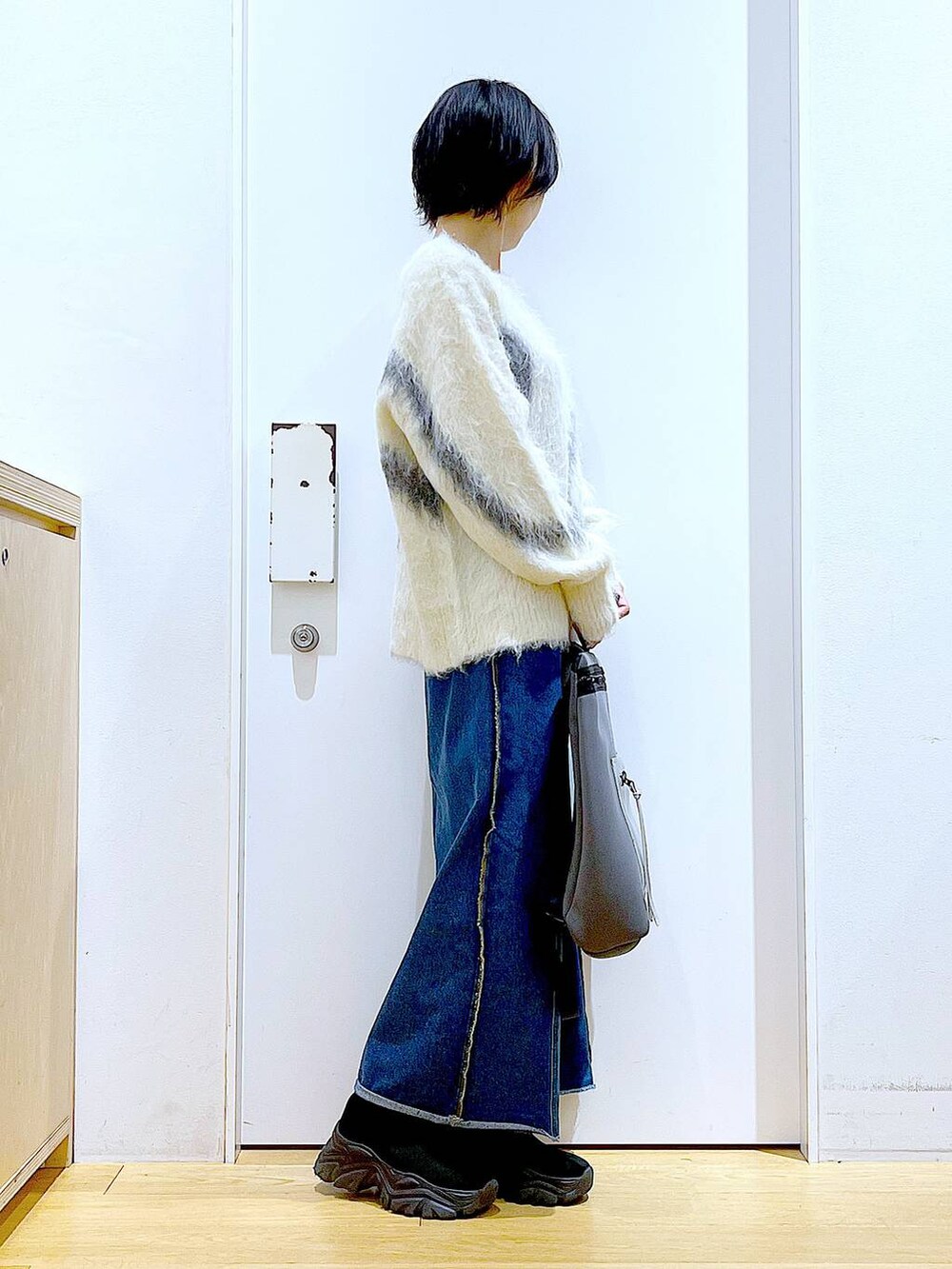ホワイト系のニット/セーター、グレー系のバックパック/リュック、ブルー系のデニムスカートを着用したレディースの冬コーディネートの4枚目の写真