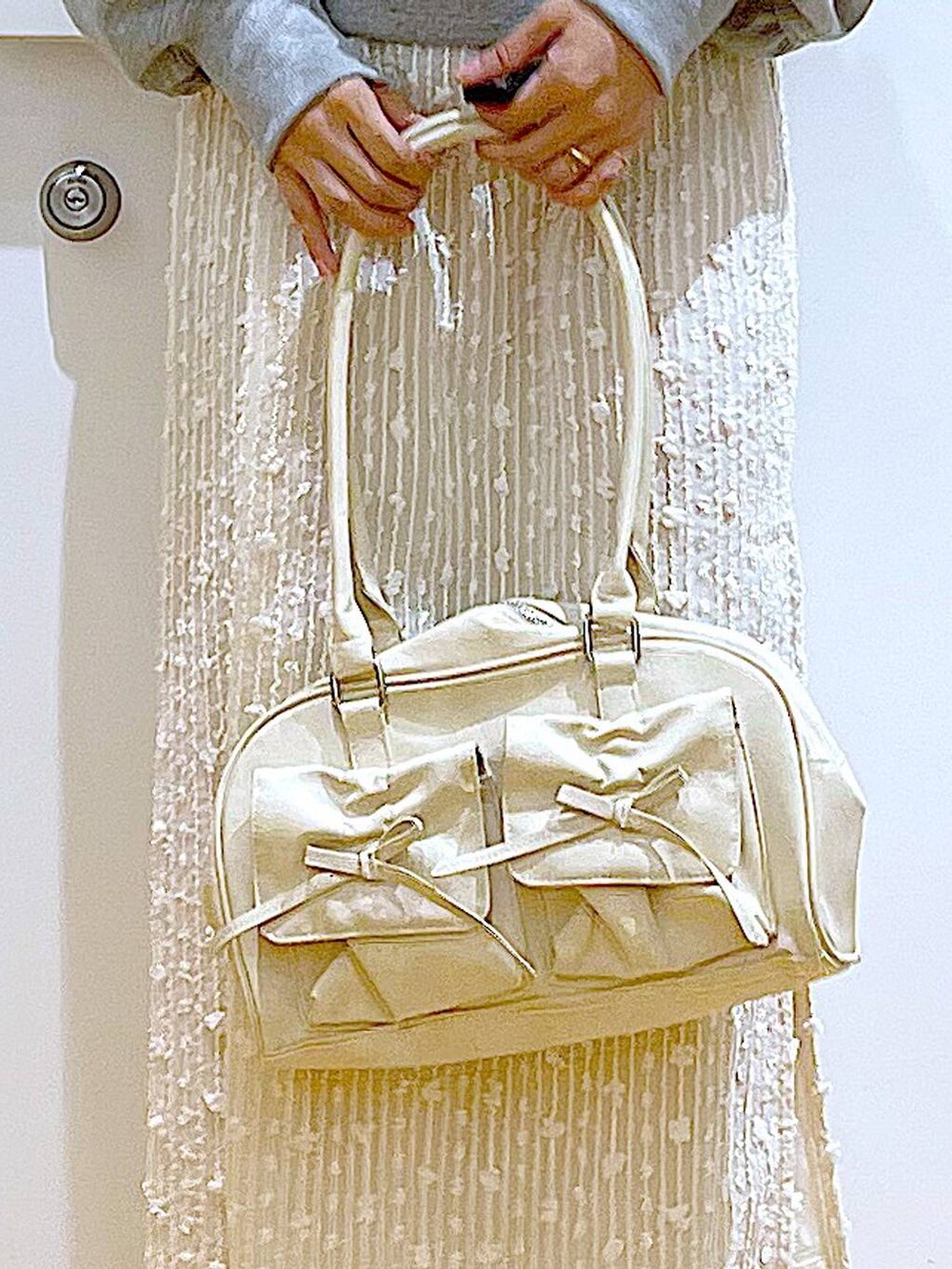 ホワイト系のハンドバッグ、グレー系のスウェット、ベージュ系のブーツを着用したレディースの秋コーディネートの9枚目の写真