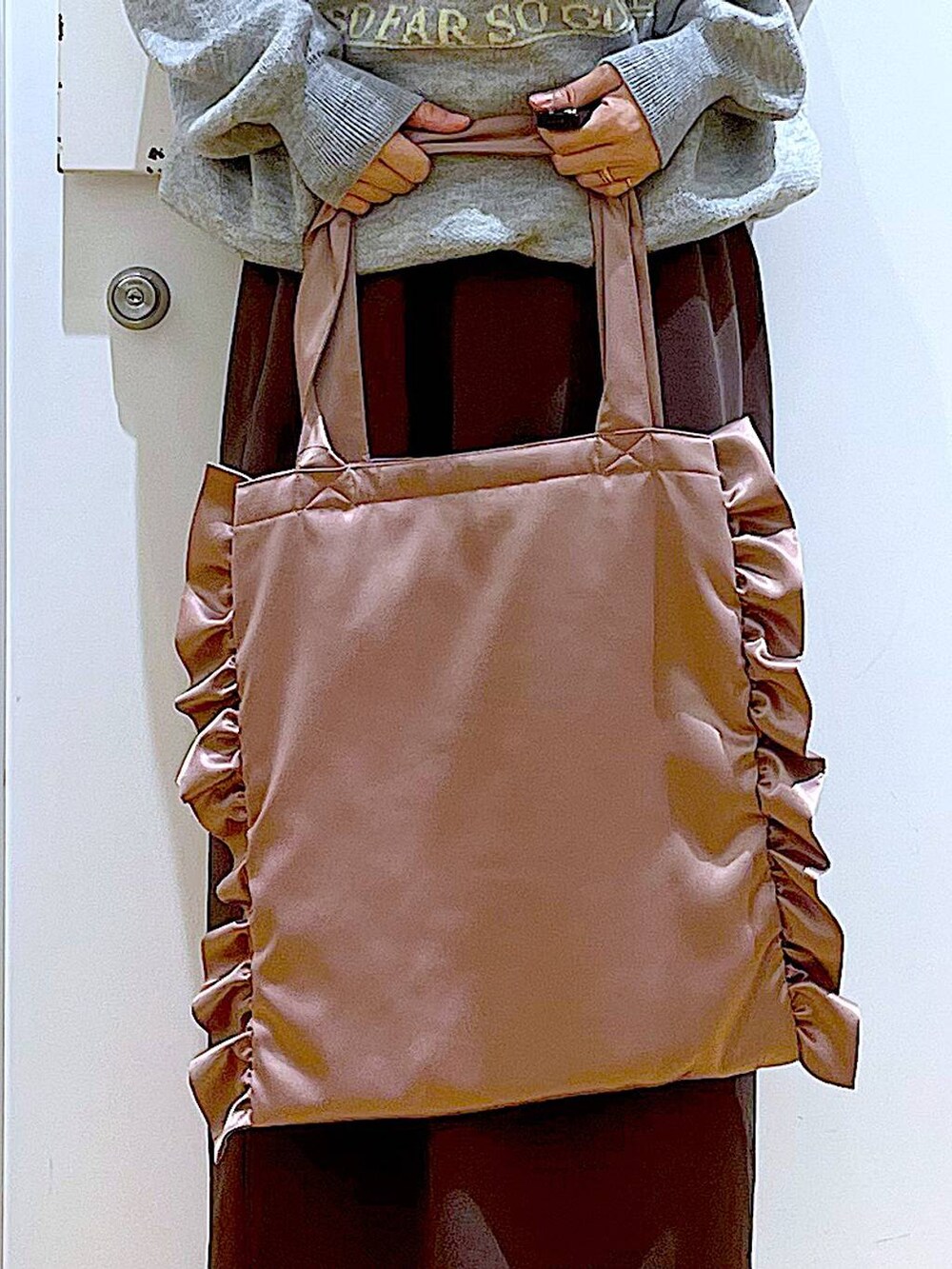 ブラック系のブーツ、ピンク系のトートバッグ、ブラウン系のスカートを着用したレディースの冬コーディネートの9枚目の写真