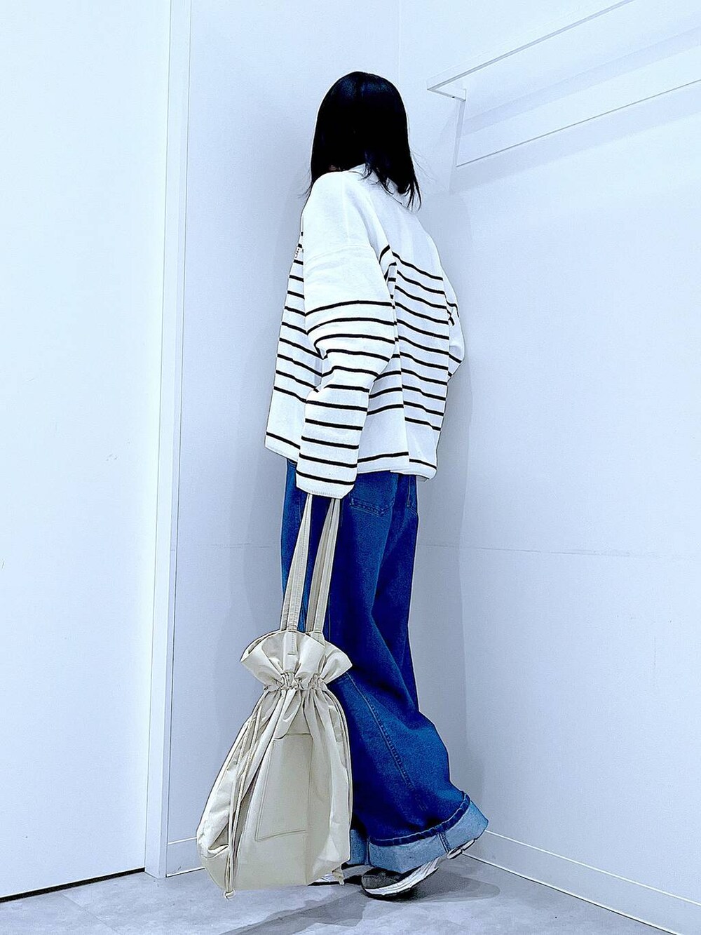 ブラック系のTシャツ/カットソー、ベージュ系のトートバッグ、ブルー系のデニムパンツを着用したレディースの冬コーディネートの3枚目の写真