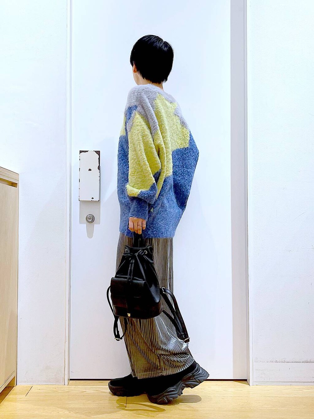 ブラック系のバックパック/リュック、グレー系のスカート、ブラック系のブーツを着用したレディースの冬コーディネートの3枚目の写真