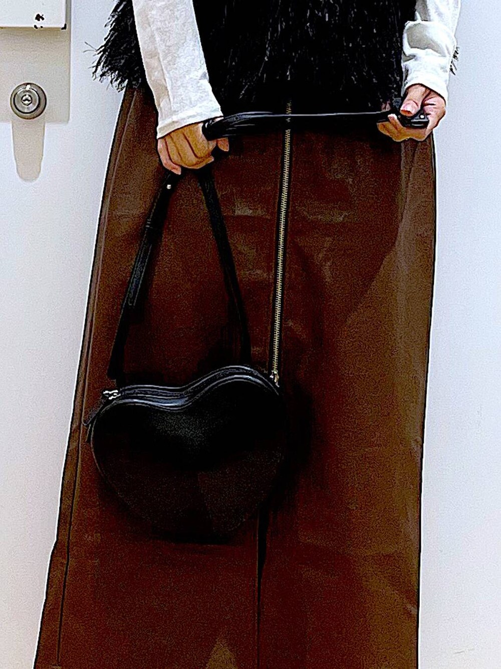 ブラウン系のスカート、ブラック系のショルダーバッグ、ホワイト系のTシャツ/カットソーを着用したレディースの秋コーディネートの9枚目の写真