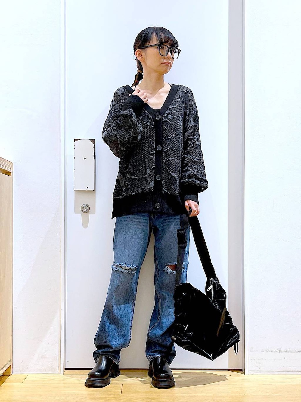 ブラック系のサンダル、ブラック系のカーディガン/ボレロ、ブルー系のデニムパンツを着用したレディースの春コーディネートの2枚目の写真