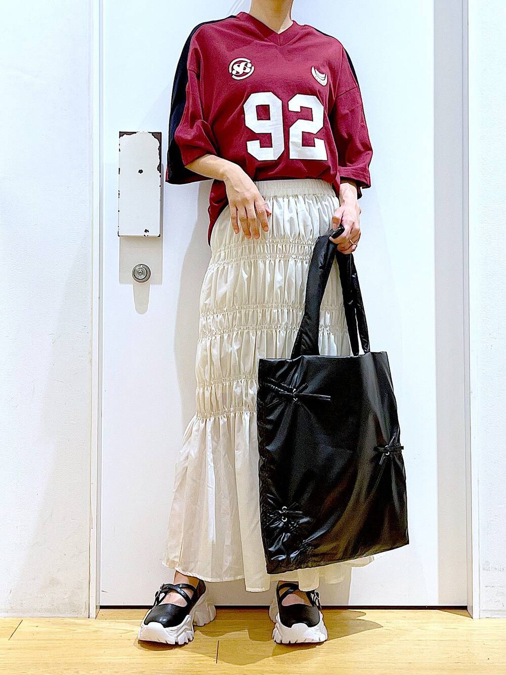 ホワイト系のスカート、ブラック系のスニーカー、ブラック系のトートバッグを着用したレディースの秋コーディネートの6枚目の写真