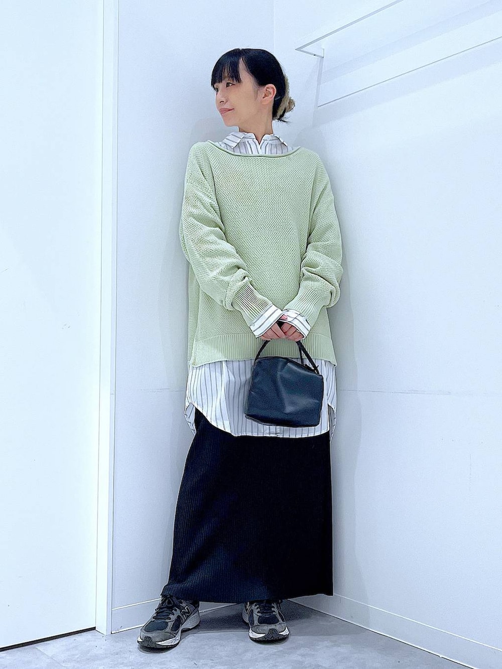 ブラック系のショルダーバッグ、ホワイト系のシャツ/ブラウス、グリーン系のニット/セーターを着用したレディースの春コーディネートの2枚目の写真