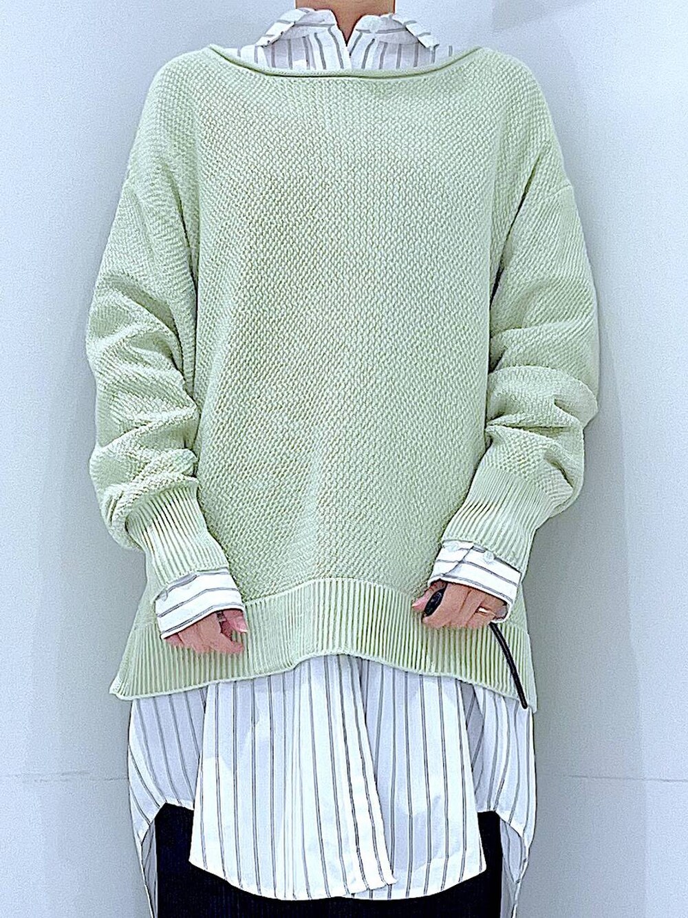 ブラック系のショルダーバッグ、ホワイト系のシャツ/ブラウス、グリーン系のニット/セーターを着用したレディースの春コーディネートの7枚目の写真