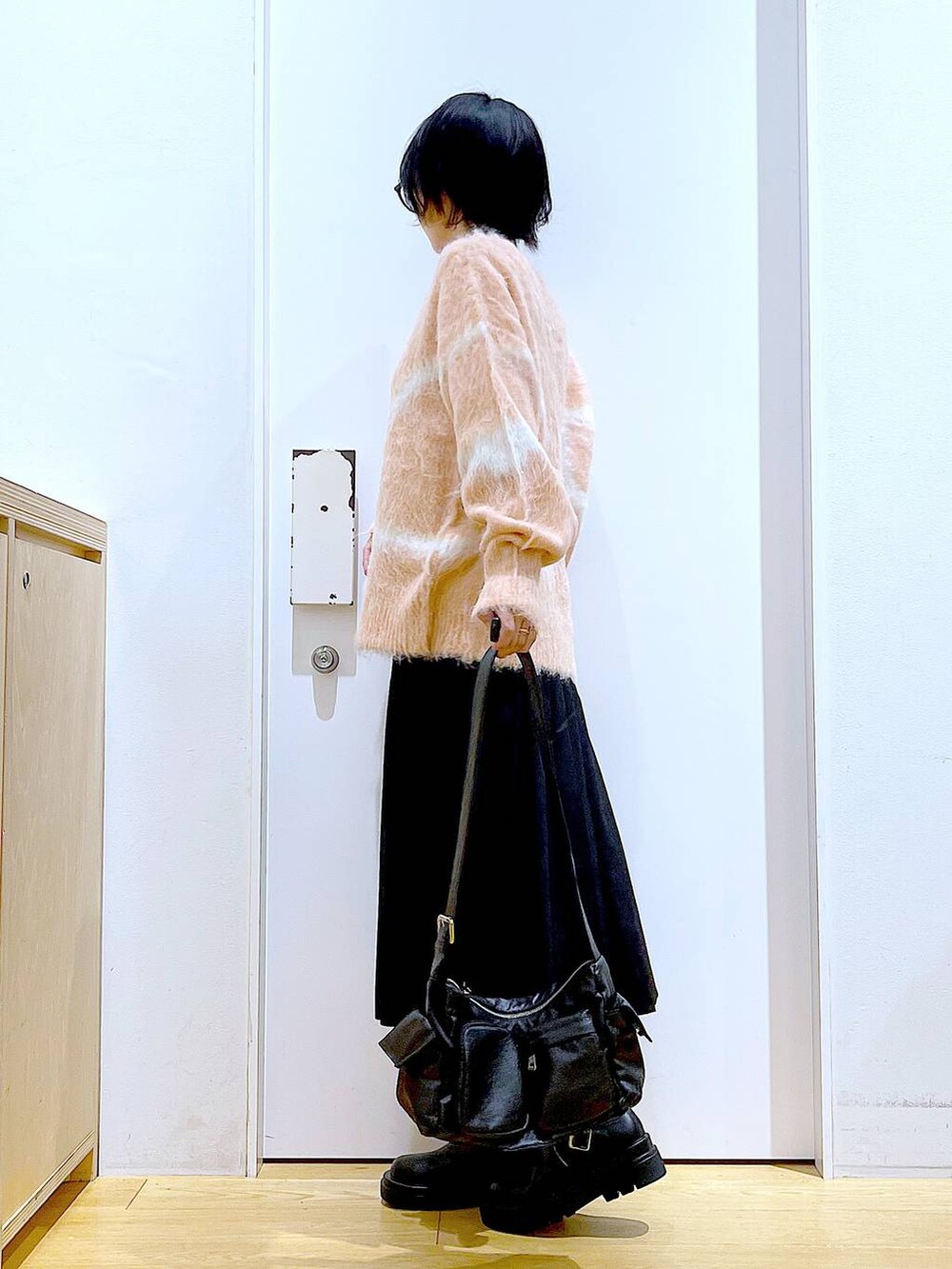 ピンク系のニット/セーター、ブラック系のブーツ、ブラック系のショルダーバッグを着用したレディースの秋コーディネートの3枚目の写真