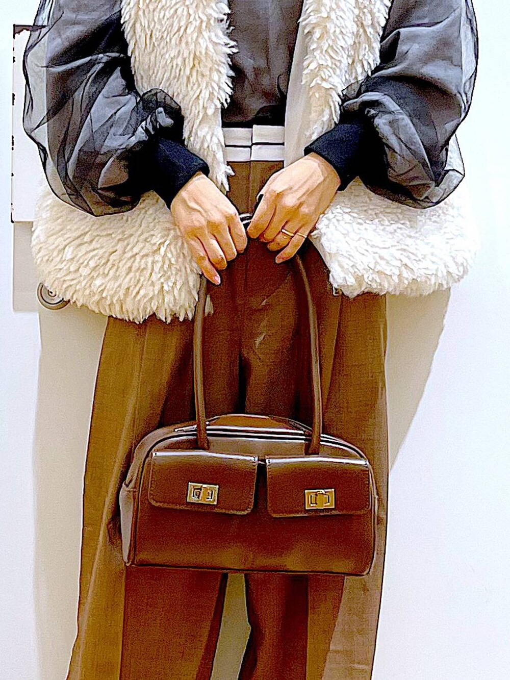 ベージュ系のベスト、ブラウン系のハンドバッグ、ブラック系のブーツを着用したレディースの冬コーディネートの9枚目の写真