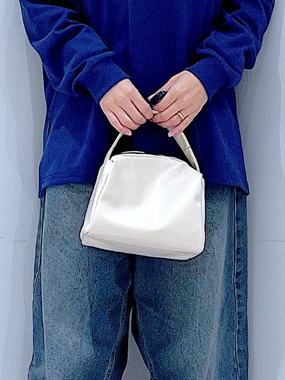 ブルー系のデニムパンツ、ホワイト系のショルダーバッグ、ブルー系のポロシャツを着用したレディースの冬コーディネートの9枚目の写真